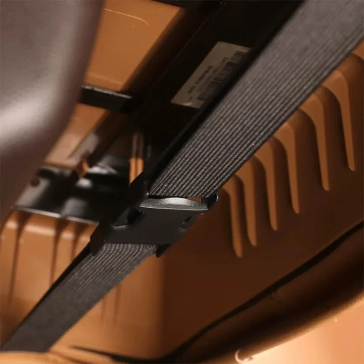 Close-up of a durable black nylon strap with a secure plastic buckle on a brown car interior.